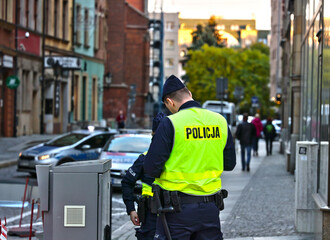 Policjant w żółtej kamizelce odblaskowej na służbie w mieście.  - obrazy, fototapety, plakaty