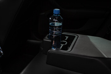 Cup holders inside modern car interior. Interior view of modern car. Bottle placed on the car cup holder.