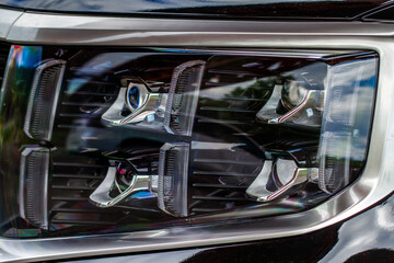 Obraz na płótnie Canvas Headlight lamp of new car. Close up detail on one of the LED headlights modern car. Exterior closeup detail. Closeup headlights of car..