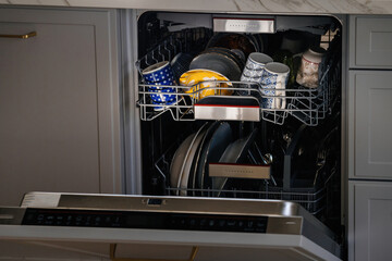 Paris, France - Jun 27, 2021: Close-up of dischwasher with multiple cups and shishes inside in modern luxury kitchen