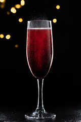 Red drink carbonated maelstrom on glass glass on black isolated background with golden bokeh