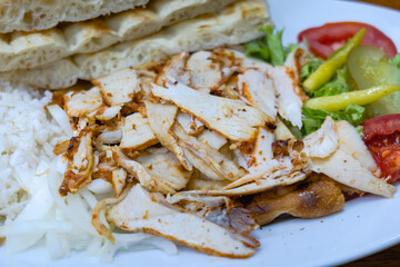 Doner Kebab, chicken kebab meat, traditional Turkish food sliced on plate with bread and vegetables