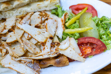 Doner Kebab, chicken kebab meat, traditional Turkish food sliced on plate with bread and vegetables