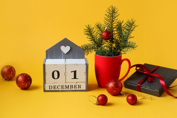 Calendar for December 1 : the name of the month in English, the numbers 0 and 1 ,a Christmas composition in a red cup, Christmas balls , a gift in a gray package, tied with a red ribbon 