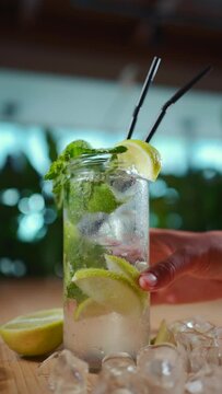 female hand with fresh mojito drink with mint and lime in glass in cafe