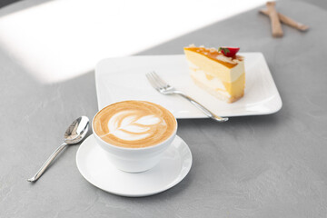 Classic cheesecake with fresh strawberry with cup of coffee on white table. Close Up view. Tasty breakfast. Piece of cake on plate, white cup on white marble background.
