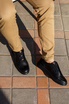 Men's sneakers or shoes made of genuine leather on men's legs close-up.