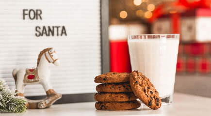 Merry Christmas 2022. Beautiful background with chocolate chip cookies and a glass of milk for Santa Claus. Celebrating the winter New Year holidays. The concept of the beginning of the year.