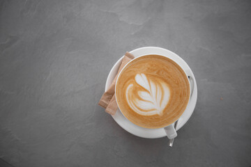 White cup of hot latte coffee with beautiful milk foam latte art texture isolated on gray background. Overhead view, copy space. Advertising for cafe menu. Coffee shop menu.