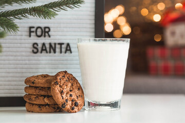 Merry Christmas 2022. Beautiful background with chocolate chip cookies and a glass of milk for Santa Claus. Celebrating the winter New Year holidays. The concept of the beginning of the year.