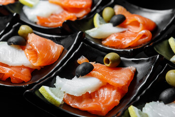 Sliced pieces of red and white fish, seasoned with olives and lemon.