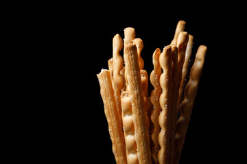 Crispy breadsticks sprinkled with sugar on a dark background.