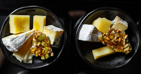 Diced cheese and nuts with honey in cups on a dark background.