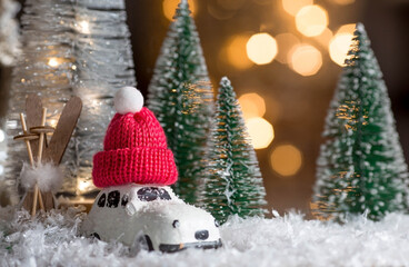 Happy New Year 2022. Beautiful background with a car with a red hat on the roof, Christmas trees and decorations. Celebrating the winter Christmas holidays. The concept of the beginning of the year.