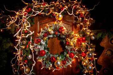 Christmas wreath with lights and toys on a wooden door.