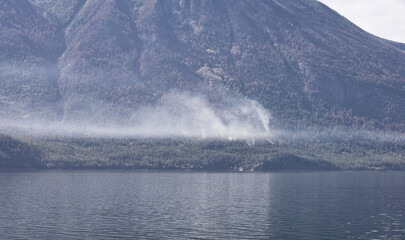 Small Wild Fire on the side of a mountain during a sunny summer day. Interior British Columbia, Canada.