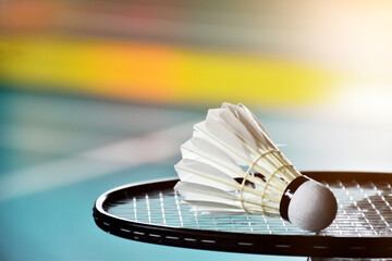 Cream white badminton shuttlecock and racket with neon light shading on green floor in indoor badminton court, blurred badminton background, copy space. - obrazy, fototapety, plakaty