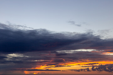 Fototapeta na wymiar lever de soleil dessus de l'océan avec un ciel orangé et des nuages 