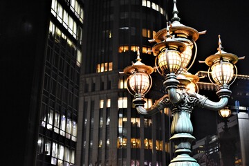 Glowing vintage street lamp illuminating the city street in the evening with office buildings at the background