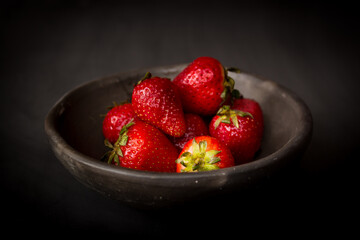 plate of fresh strawberries on dark background