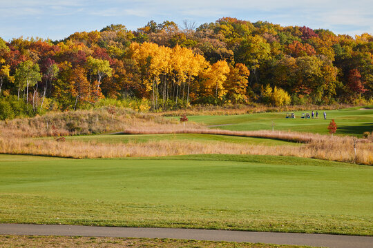 Golf course on a beautiful fall day with green grass and leaves changing into vivid colors