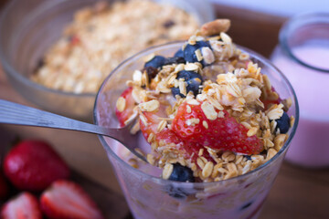 spoon serving yogurt, cereal, strawberries and blueberries