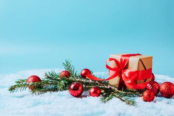 Festive box with a red bow on a blue background with Christmas toys balls branch of fluffy spruce sparkles and confetti . New Year Christmas concept. Flat festive mockup with copy space