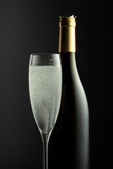 Bottle and glass of champagne on a black background.
