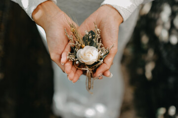 bride in white holding wedding flower corsage in her hand during her wedding day