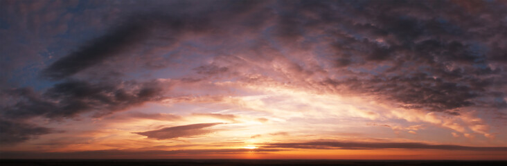 Dramatic sky at sunset or sunrise. Dark mystical clouds. Bright sunlight in blurred orange clouds.