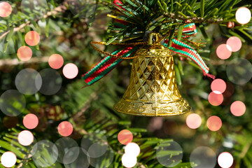 Christmas background. Bokeh. A Christmas bell hangs on a spruce branch.