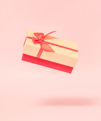 modern abstract christmas gift box in the air  against pastel pink background. futurisam. minimalism. modern creative decoration idea for 2022 new year