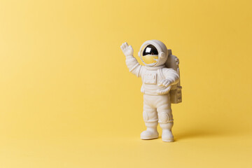 Plastic toy figure astronaut on a yellow background. Copy space. Close-up. The concept of space and...