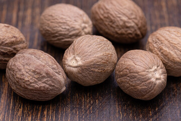Nutmegs on a wooden brown background. Close-up, horizontal studio shot.