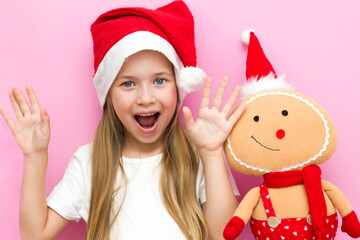 Christmas Eve! A cheerful child in a Christmas hat on a pink background.