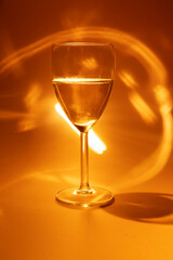 glass of white wine on orange background with lights and glitters
