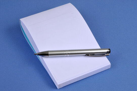 Stylo pos&eacute; sur un bloc-notes en gros plan sur fond bleu