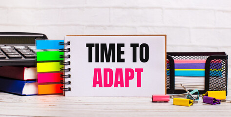 On a light wooden background, a calculator, multi-colored sticks and a notebook with the text TIME...