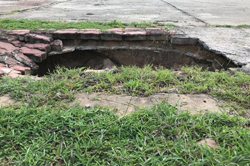 A big hole at the footpath in the city. The dangerous problem for travel.