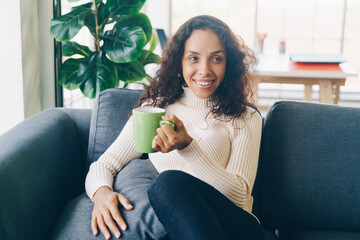 Latin woman drinking coffee on sofa