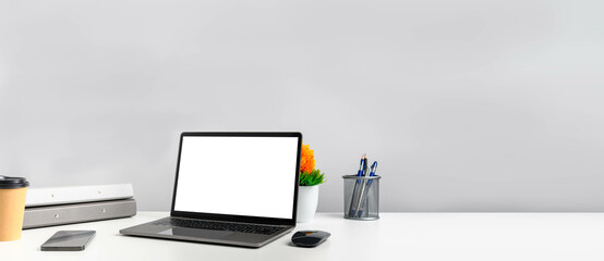 Copy space on right for design or text. Working concept using technology smartphones, notebook, internet. Blank white screen laptop on white table in the office. Closeup, Gray, and blurred background