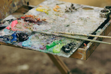 Shallow depth of field (selective focus) image with a painter color palette while painting a landscape on a sunny autumn day.