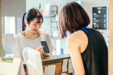 受付でスマホを出す女性

