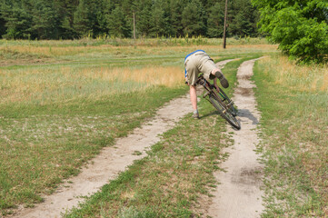 Mature man falling off of an ancient bicycle on a country road in rural village in central Ukraine