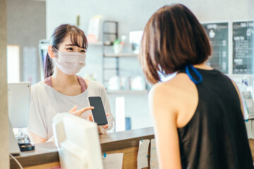 受付でスマホを出す女性（マスク）
