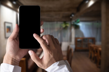 Hand holding mobile phone with blank  screen at cafe in the morning.