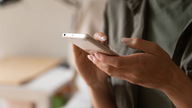 Hands of woman holding smartphone, using online app and virtual services cellphone, making video phone call, texting and chatting on messengers, buying online, reading books, articles. Close up
