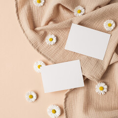Blank paper sheet card with mockup copy space, chamomile flower buds and muslin cloth on neutral...