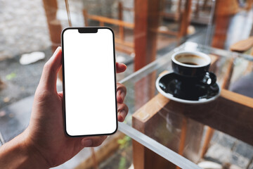 Mockup image of a man holding mobile phone with blank white screen in cafe