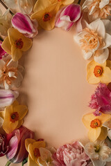 Aesthetic flat lay frame with colourful roses, narcissus, tulip flowers and petals on neutral ginger background. Top view blank copy space template